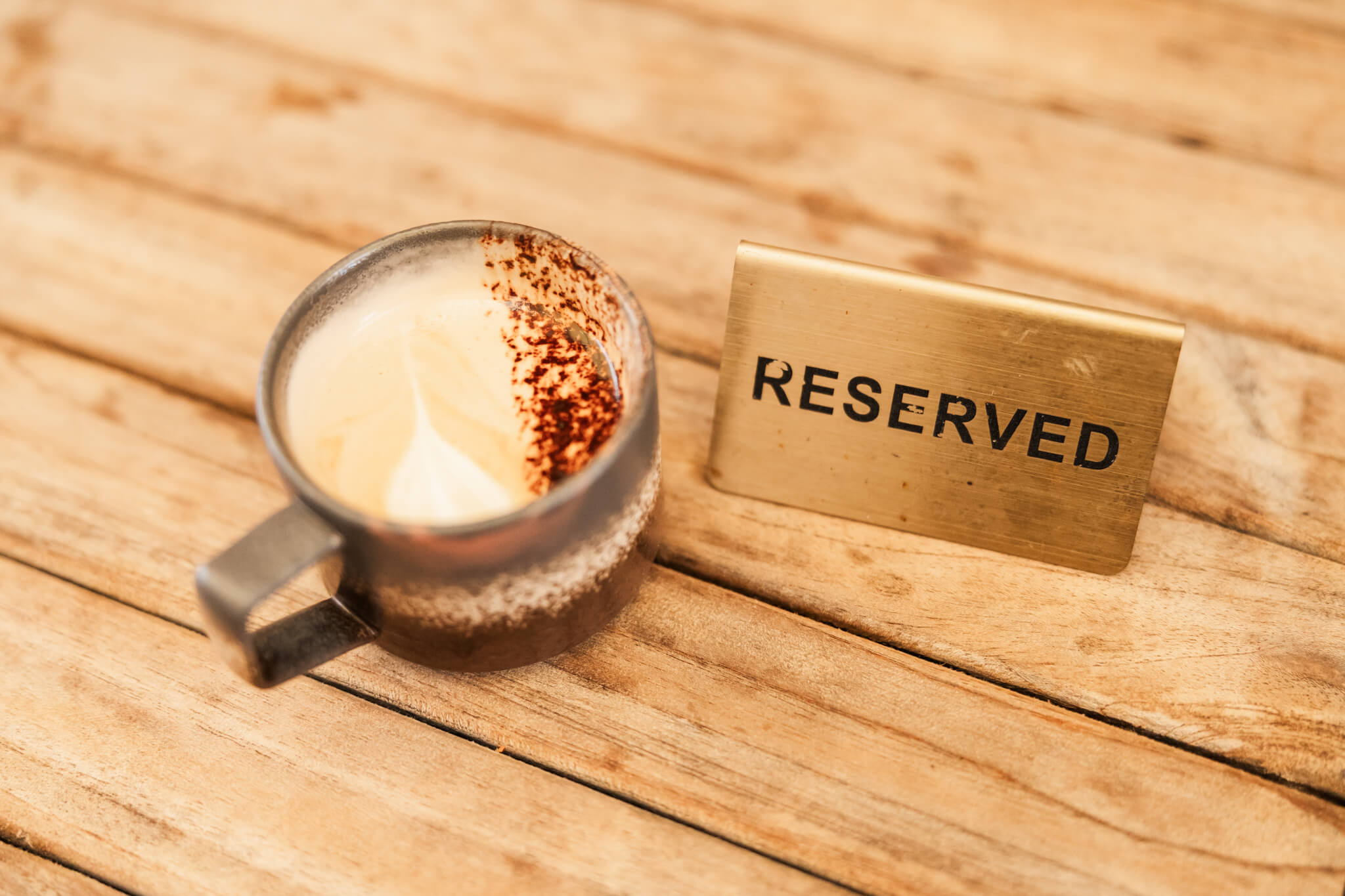 A cup of coffee on offer at a catch up event organised by the Capricornia Chamber of Commerce. Coffee cup sitting next to a reserved sign on a table.