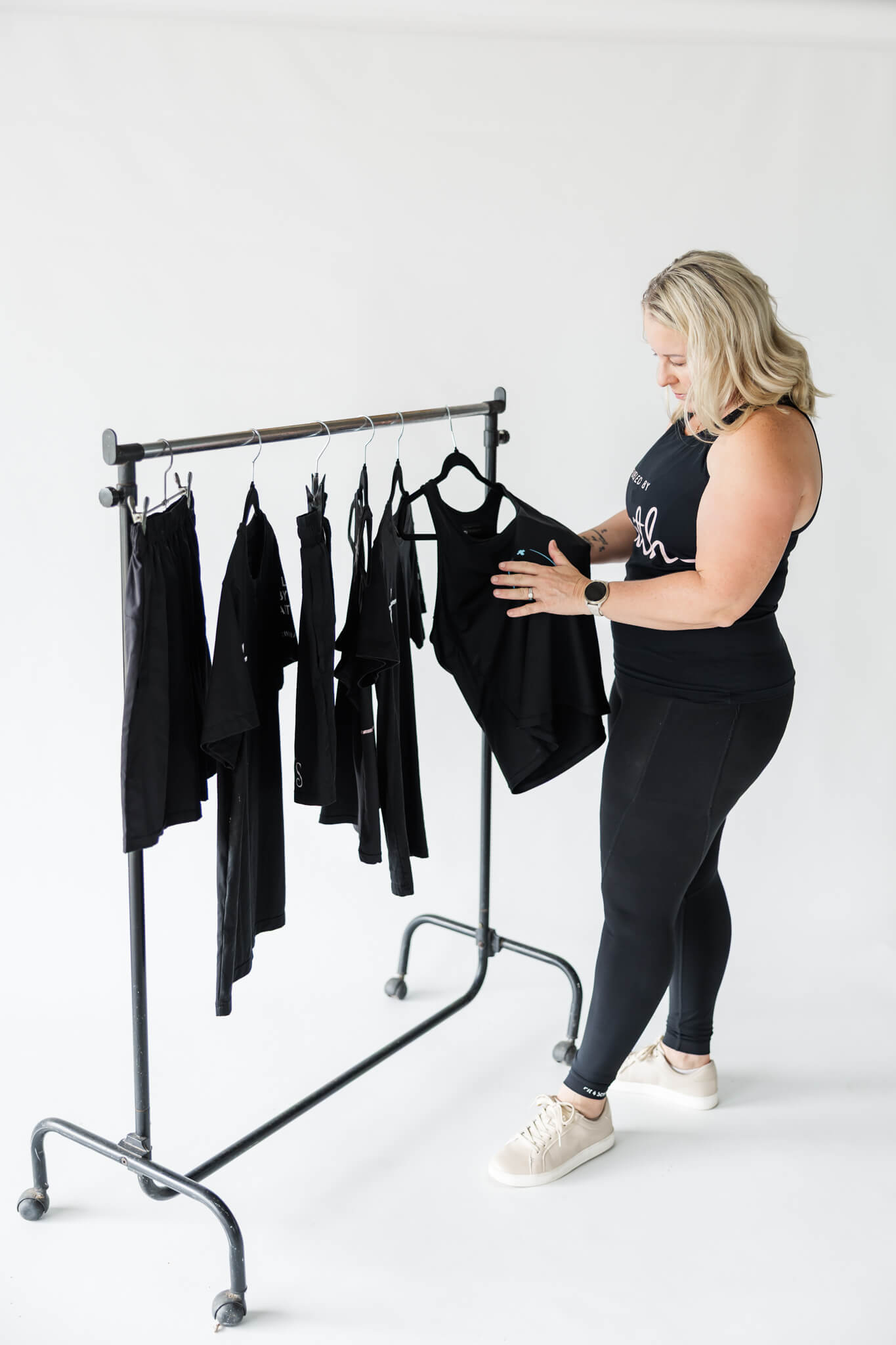 A blonde lady looking at fitness wear products, dressed in leggings and a tank top.